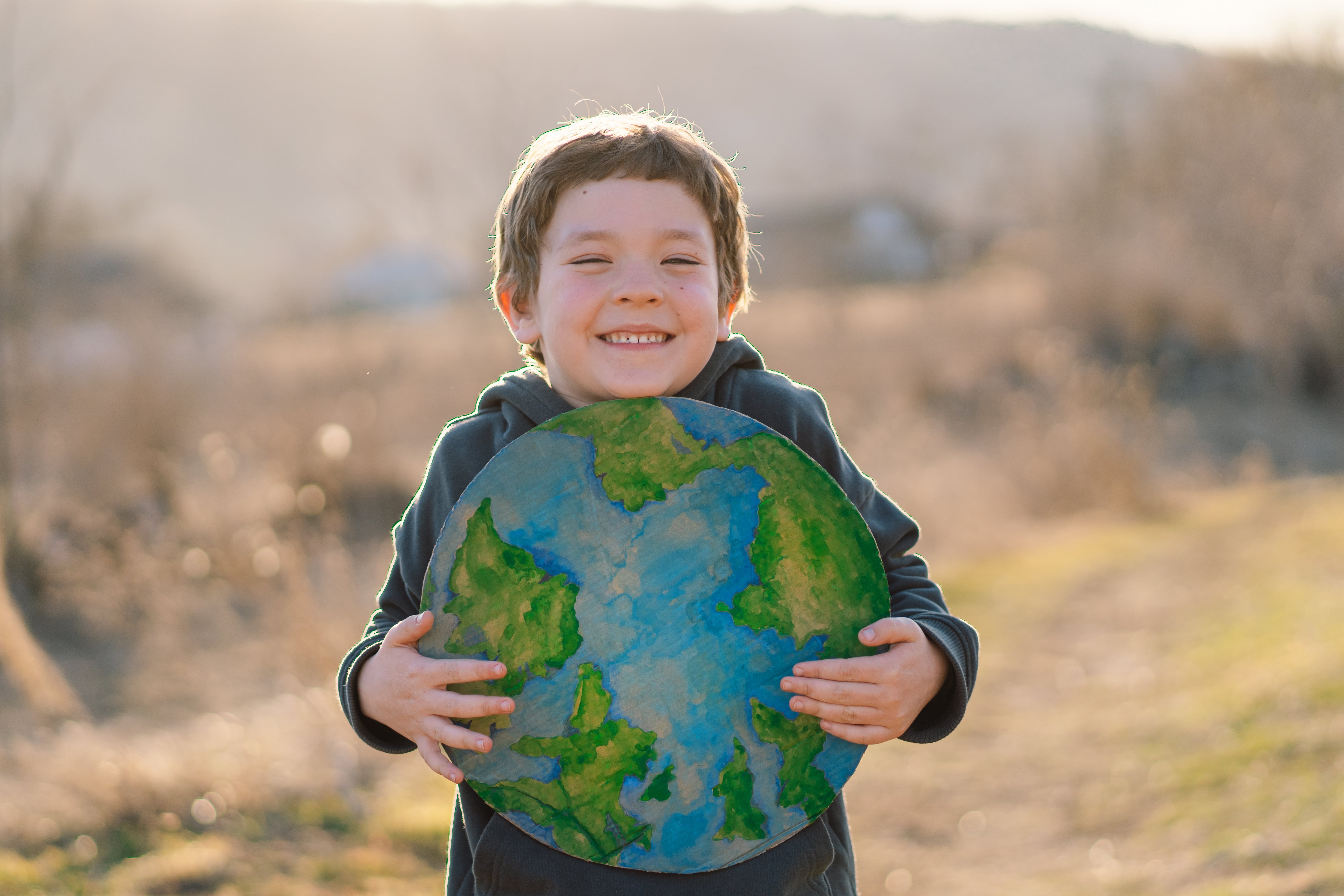A young boy holding a cutout of the globe and smiling. 